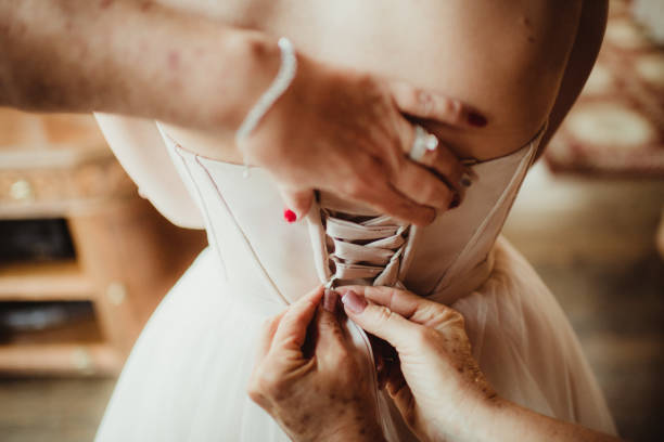 Bride wearing corset style wedding dress with mother helping her get ready